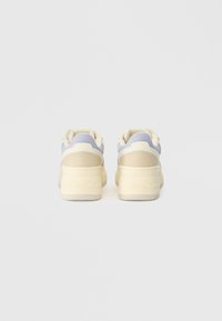 Tennarit, joissa on kerma- ja vaaleansiniset värit, sileä pinta, pehmustettu kaulus ja kohotettu pohja, jossa on kohokuvioitu brändäys kannassa.