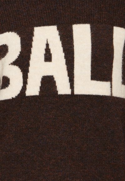 Rjav pleteni pulover z velikimi kremnimi črkami, ki črkujejo "BALD" čez prsi. Mehek material z rahlo puhasto površino.