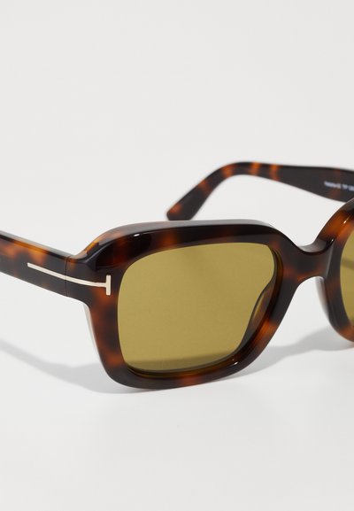 Schildpatt-Sonnenbrille mit einem dicken Rahmen, quadratischer Form, olivgrünen Gläsern und silbernen Akzenten an der Seite. Leichtes Kunststoffmaterial.