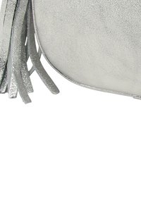 Silberne Clutch aus Wildleder mit weicher Textur, abgerundeter Form und Fransen-Details auf einer Seite. Minimalistisches Design ohne sichtbare Beschläge.