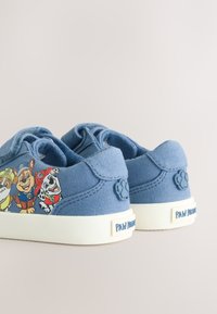 Chaussures en toile bleue pour enfants avec un motif d'un personnage de Pat'Patrouille sur le côté, semelle en caoutchouc blanche et panneau arrière texturé.