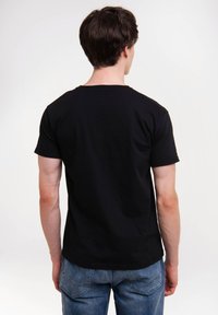 Black short-sleeve t-shirt with a crew neck, made of cotton. Straight cut and simple design, shown from the back, paired with blue jeans.