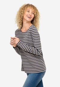 T-shirt rayé à manches longues en bleu marine et crème, avec un col rond et une coupe décontractée, associé à un jean en denim bleu. Tissu à texture douce.