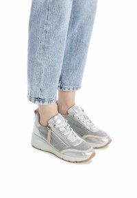 Zapatillas plateadas con malla y detalles metálicos, que presentan un diseño de cordones y cremallera lateral. Suela elevada y puntera redondeada.