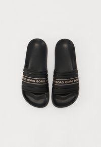 Svart sandaler i plast med tre horisontale stropper. Designet har gjentatt "BORG"-tekst i gull på stroppen.