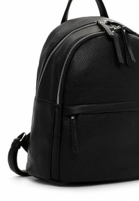 Mochila de cuero negro con textura aterciopelada, que cuenta con dos compartimentos con cremallera, un bolsillo frontal y correas de hombro ajustables.