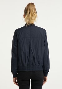 Navy blauwe lichtgewicht jas met een ronde kraag, elastische manchetten en zoom, met een gladde, glanzende textuur en subtiele stikseldetails.