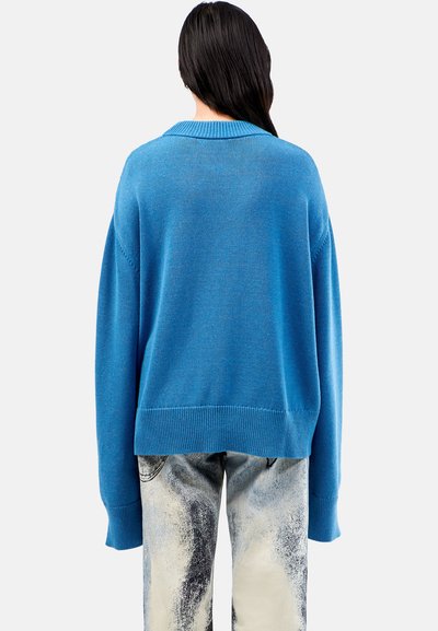 Blue knit sweater with a ribbed crew neckline, dropped shoulders, and a relaxed fit. Detailed with textured patterns and long sleeves.