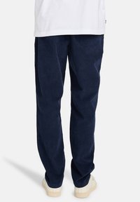 Pantalones de pana en color marino con un diseño de pierna recta, tela texturada y cinturilla elástica. Presenta una sutil costura decorativa y bolsillos laterales.