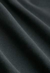 Tela negra con una textura suave, que presenta suaves pliegues fluidos y un brillo sutil, mostrando un patrón de tejido apretado.