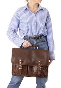 Borsa a spalla in pelle marrone con pattina, due tasche frontali e hardware color oro. Presenta dettagli cuciti e una maniglia superiore per il trasporto.