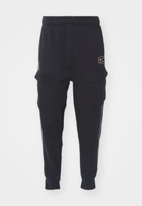Pantalones de chándal negros hechos de una tela suave, con bolsillos tipo cargo, cintura elástica y rayas laterales blancas. Detalle del logo dorado en la parte delantera.