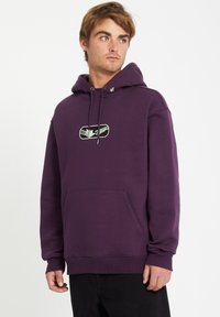 Paarse hoodie van zacht materiaal, met een voork pocket, een capuchon met trekkoord en een grafisch logo op de borst. Eenvoudige geribbelde manchetten.