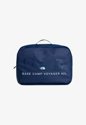 Marineblauwe inpakcube met handvat, gelabeld "Base Camp Voyager 62L" en lijntekeningen van een rugzak, duffeltas en draagtas aan de voorkant.