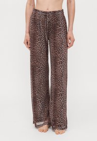 Lightweight, loose-fitting beige pants with a leopard print pattern, featuring an elastic waistband and drawstring for adjustable fit.