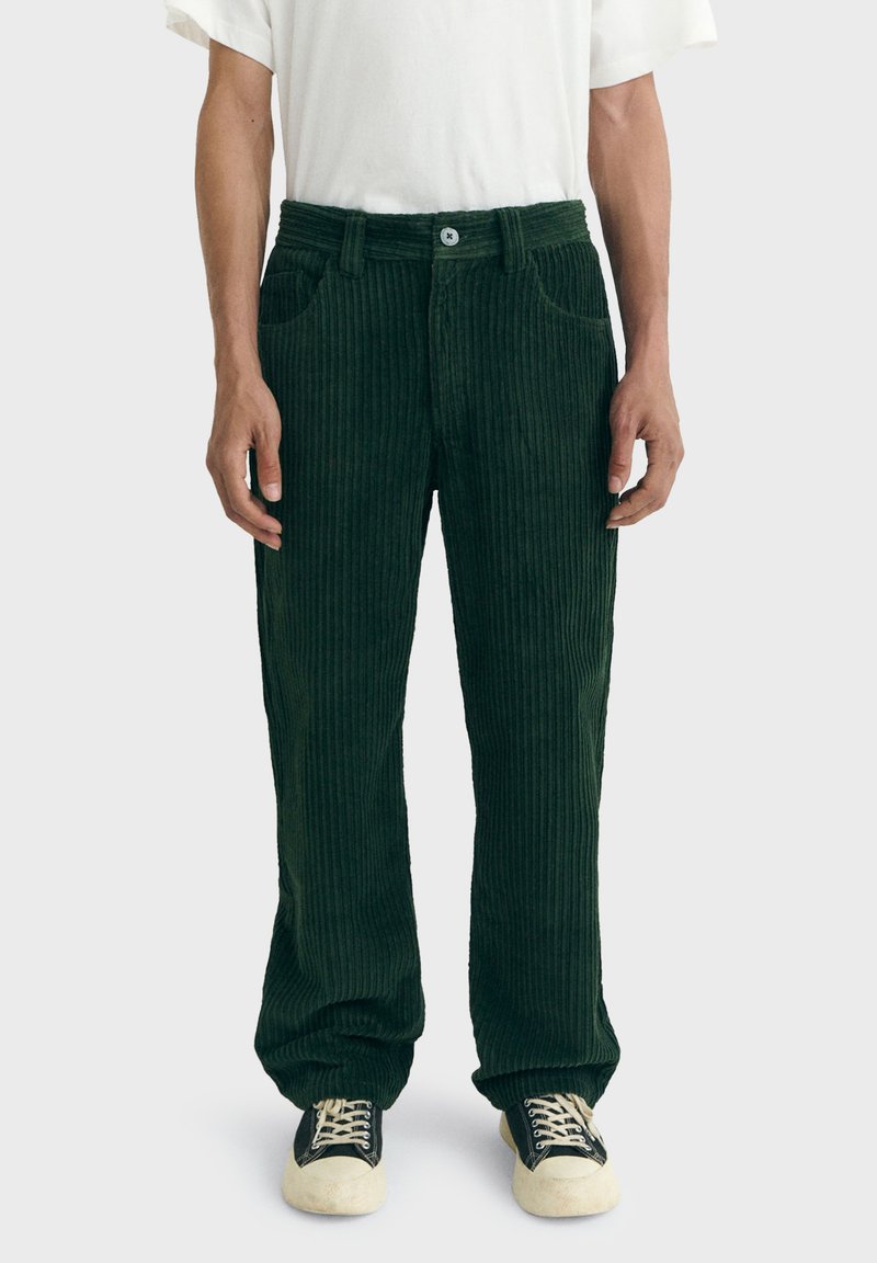 Pantalones de pana verde oscuro con corte recto, que cuentan con cierre de botón, bolsillos frontales y un patrón de relieve texturizado.