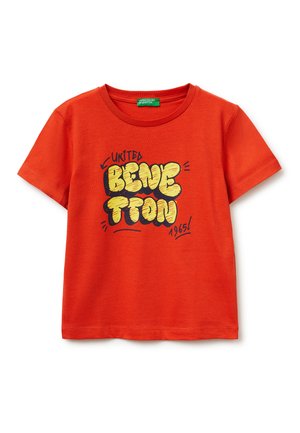 Czerwona koszulka z krótkim rękawem z żółtym i czarnym tekstem w stylu graffiti "United Benetton 1965" z przodu oraz zieloną metką marki wewnątrz kołnierza.