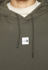 Olivově zelená mikina s kapucí vyrobená z měkké látky, s přední kapsou a obdélníkovou visačkou s logem "The North Face".