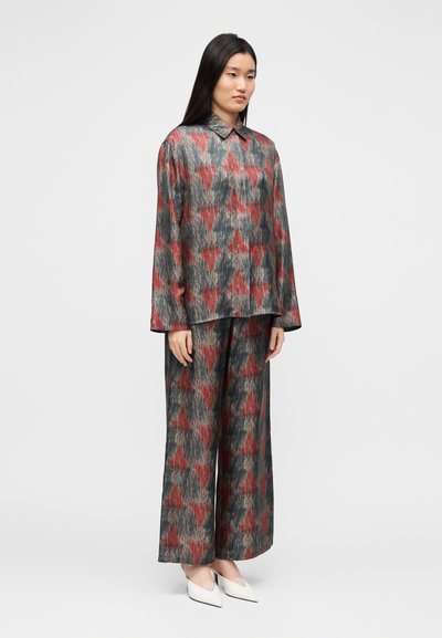 Løs pasform, mønstret outfit i mørkegrå, rød og hvid med en skjortekrave og bukser med vidde ben; glat tekstur og lange ærmer.