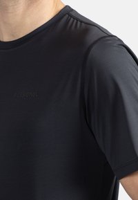 Svart kortärmad träningsskjorta i slät, andningsbar tyg. Har subtil ton i sömmarna och en upphöjd logotyp på bröstet.