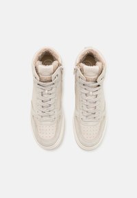 Paire de baskets montantes beiges à lacets et zips latéraux, avec une doublure intérieure douce et duveteuse et des bouts perforés.