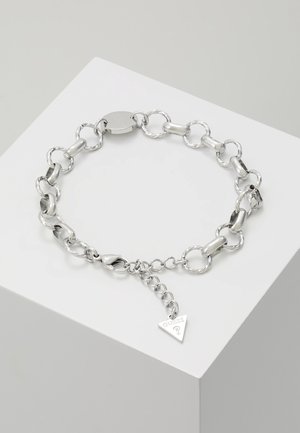 Srebrna bransoletka z okrągłymi i cylindrycznymi ogniwami, zapięciem typu karabińczyk oraz małym trójkątnym zawieszkiem z grawerem "GUESS ?"