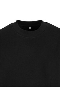 Sudadera de algodón negra con un cuello a la caja acanalado. La tela parece suave, con una textura mínima y sin patrones o acentos visibles.
