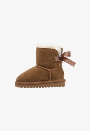 Brown suede ankle boot with white fur lining and a decorative brown ribbon tied at the back, flat rubber sole.
