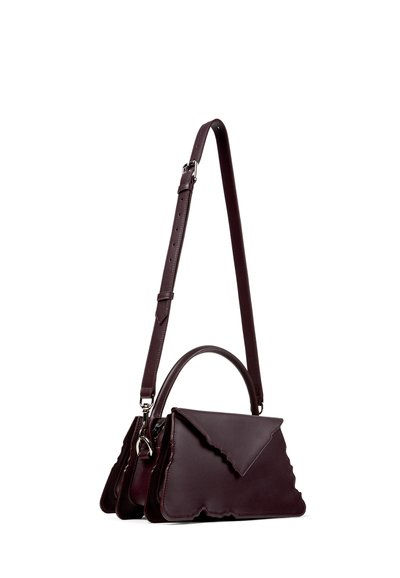 Sac à main en cuir bordeaux foncé avec des bords festonnés, une poignée supérieure et une longue bandoulière réglable.