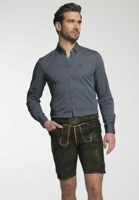 Pánský outfit s košilí s námořnickými puntíky na knoflíky a hnědými semišovými lederhosen se skládáním a kontrastním zlatým páskem.
