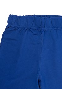 Blue cotton pants with an elastic waistband, smooth texture, and no additional patterns or accents. Close-up view of the top section.