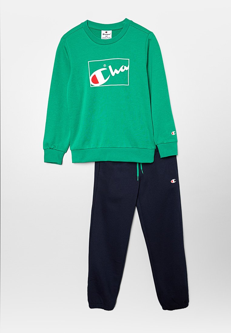 Sweatshirt vert avec logo blanc, accompagné d'un pantalon de survêtement bleu marine avec taille élastique et poignets. Les deux sont fabriqués dans un tissu doux.