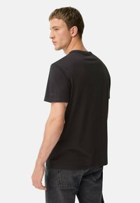 Schwarzes Kurzarm-T-Shirt mit Rundhalsausschnitt und glatter Textur, mit minimalen Nähdetails und einem dezenten Logo am Ärmel.