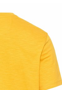 Kortærmet t-shirt i lys gul, med en blød tekstur og et meleret mønster. Rund halsudskæring og rene syninger.