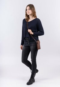 Námořnický pletený svetr, černé džíny s vysokým pasem a černé boty na šněrování. Obsahuje hnědou křížovou tašku s klopou a popruhem.