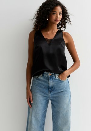 Black satin tank top with lace neckline detail, paired with high-waisted, light blue wide-leg jeans. Smooth texture and relaxed fit.