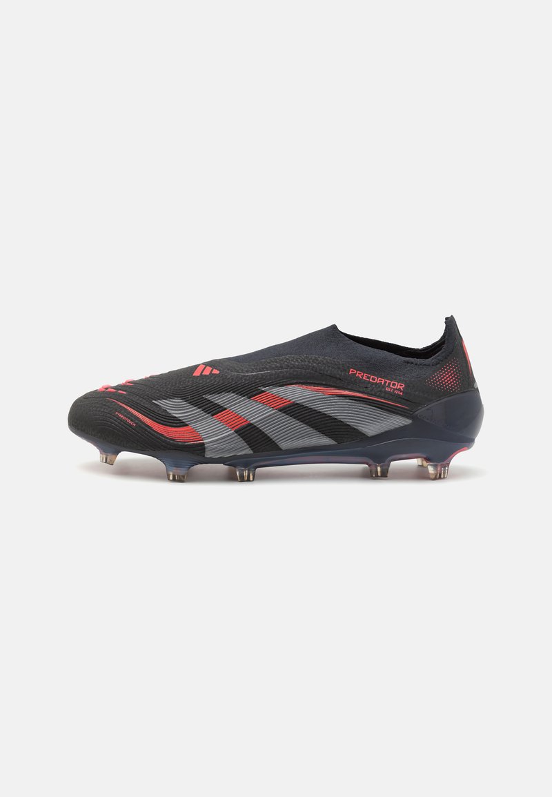 Chuteira de futebol preta e cinza com detalhes em vermelho, parte superior texturizada, design baixo e cravos cônicos para tração em superfícies de relva.