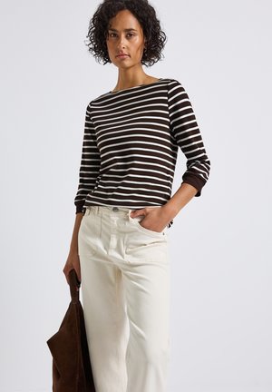 Haut à manches longues rayé marron et blanc avec un col bateau, associé à un pantalon large crème et un sac fourre-tout marron.
