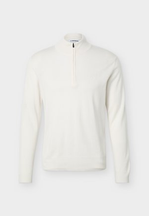 Hvid langærmet pullover med en halv-lang lynlås ved kraven og ribstrikkede ærmeafslutninger og kant, vist på en ensfarvet baggrund.