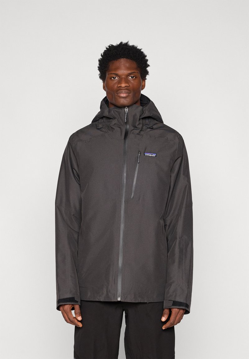 Čierna vodotesná bunda so zipsom vpredu, nastaviteľnou kapucňou a elastickými manžetami. Obsahuje malé logo na hrudi a má štýlový dizajn.