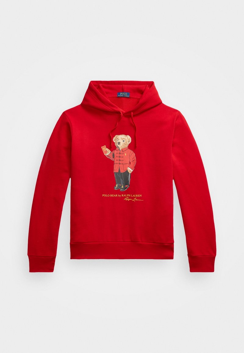 Sweat à capuche rouge avec un ours portant une veste rouge et un pantalon noir, tenant une clochette, avec le texte « Polo Bear by Ralph Lauren » en dessous.