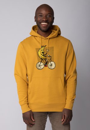 Geel hoodie met een vooraanstaande afbeelding van een cartoon banaan die op een fiets rijdt. Inclusief een kangoeroezak en ribgebreide manchetten en zoom.