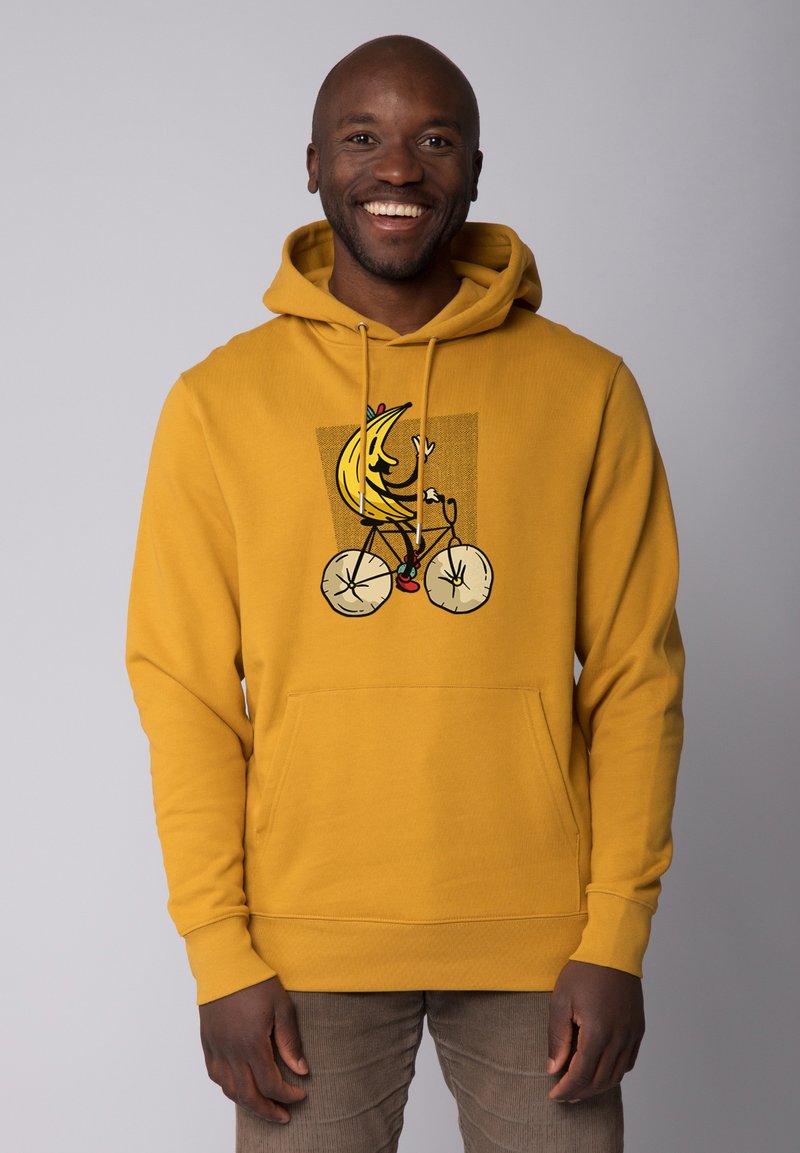 Gelber Hoodie mit einem vorderen Grafikdruck eines Cartoon-Bananas, die Fahrrad fährt. Mit einer Kängurutasche sowie gerippten Bündchen und Saum.