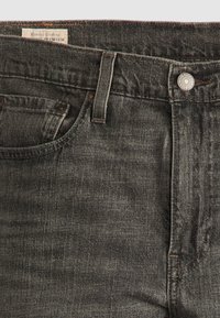 Jeans din denim gri închis cu o finisare texturată, având o jantă frontală, închidere cu buton metalic și detalii cusute de-a lungul taliei.