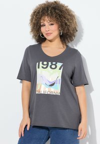 Šedé tričko s krátkým rukávem a kulatým výstřihem má barevný grafický potisk s hamakem a palmami, doplněný textem "1987 CALIFORNIA".