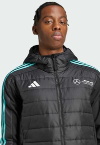 Sort polstret jakke med lynlås, hætte og turkise detaljer. Adidas- og Mercedes-logoer prydeligt vist på brystet.