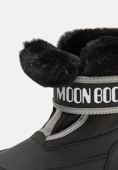 Botte noire imperméable dotée d'un large revers en fausse fourrure, d'accents gris et d'un audacieux logo "MOON BOOT" sur une sangle en tissu. Détails de surface texturée.