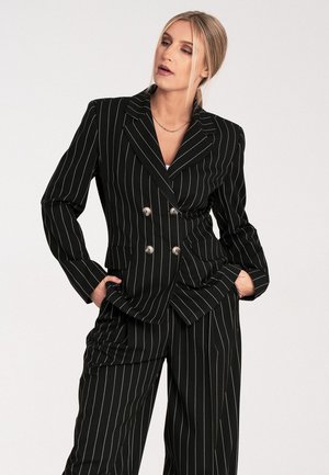 Black pinstripe suit with double-breasted blazer and wide-leg trousers. Features silver buttons and two front pockets. Smooth fabric texture.