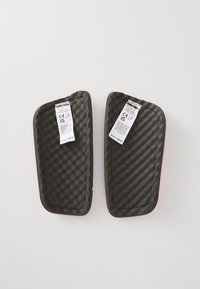 Two black protective pads with a textured surface and wavy edges, each featuring a white label with safety and product information.