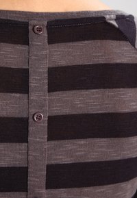 Gestreifter Strickpullover in Dunkelgrau und Hellbraun, mit einer geknöpften Rückseite und einer weichen Textur. Das Muster wechselt zwischen breiten und schmalen Streifen.